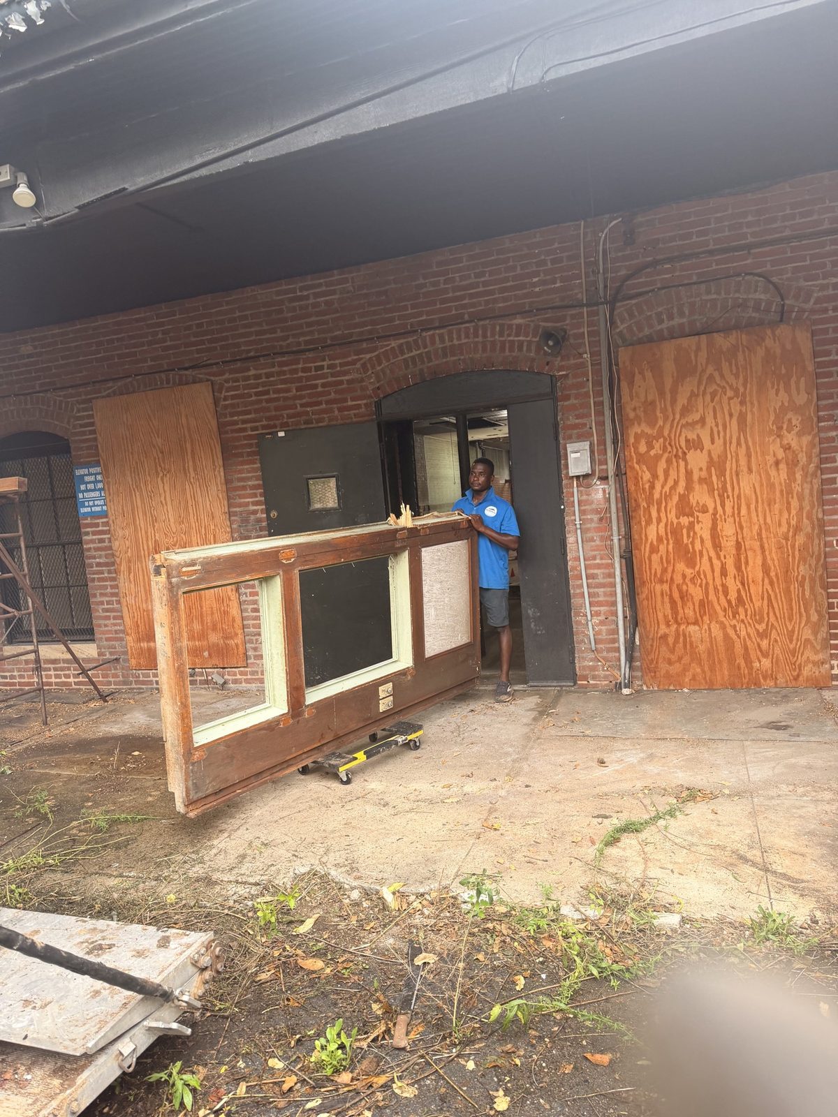 Crew member moving a large door out of a brick building