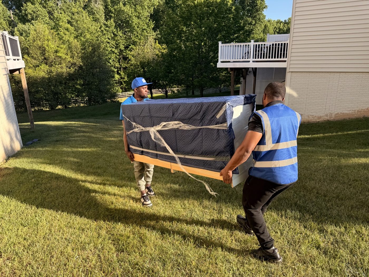 Two movers carrying a wrapped mattress